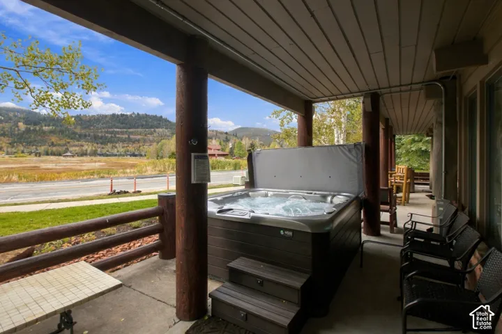 Covered patio featuring a built-in hot tub with steps, log columns, and a plank ceiling