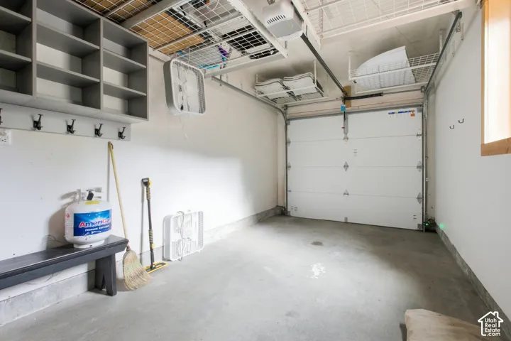 Integrated shelving and coat rack, durable concrete flooring, overhead storage racks, automatic garage door opener, and a window for natural light