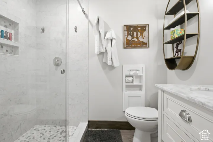 Glass-enclosed shower with white marble-style wall tiling and hexagonal floor tiling