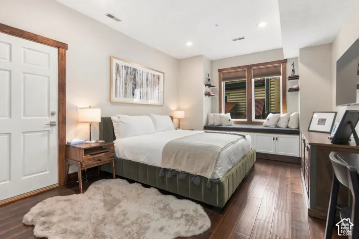 Wood-finish flooring, built-in window seating with storage, recessed lighting, and a white paneled door with wood trim
