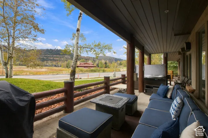 Covered patio featuring a hot tub, log fence, and mountain backdrop
