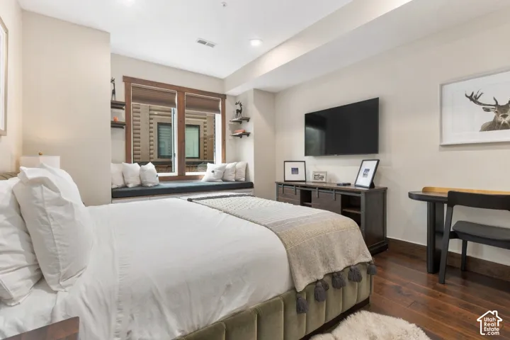 Built-in window bench with wood-framed windows, dark wood-finish flooring, recessed lighting, and wall-mounted television