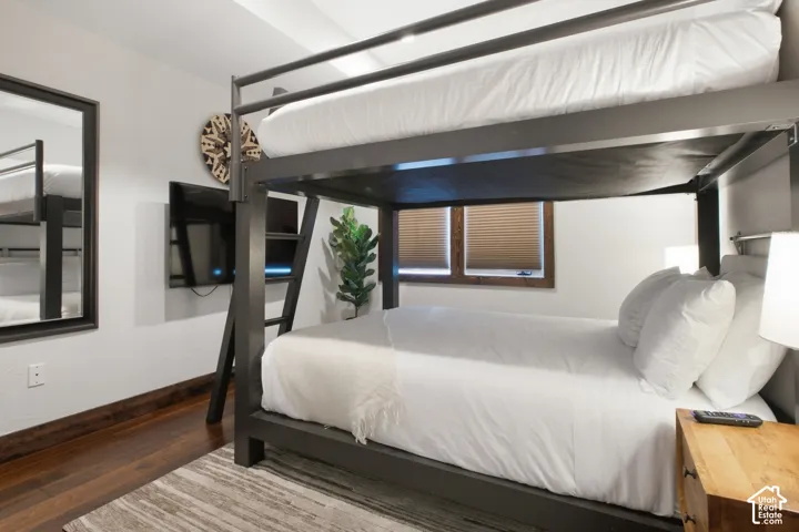 Built-in bunk beds with integrated ladder, wood-finish flooring, and two windows with privacy blinds
