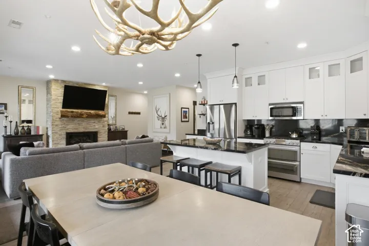 Open-concept living space featuring a stacked stone fireplace with a wood mantle, recessed lighting, and wood-finish flooring