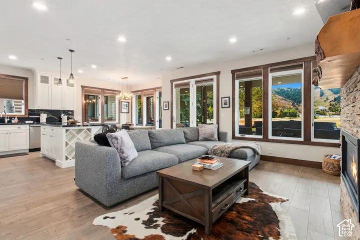 Open-concept living area featuring wood-finish flooring, a stone-clad fireplace, and recessed lighting