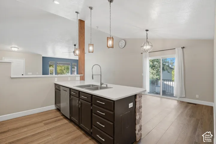 Kitchen island with integrated sink, stainless steel dishwasher, and stone-clad end panel