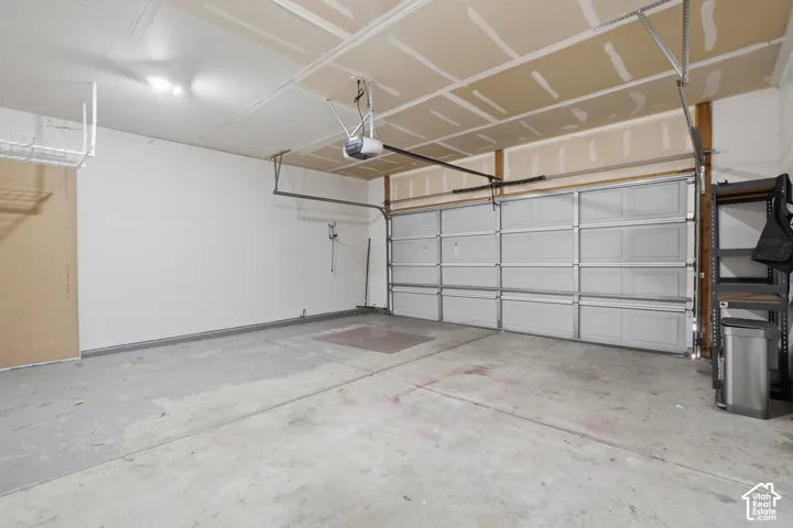 Concrete flooring, overhead garage door, automatic garage door opener, overhead lighting, wall-mounted storage rack