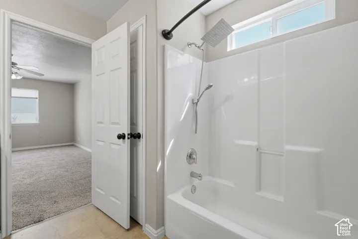 White shower/tub combination with chrome fixtures and an overhead transom window