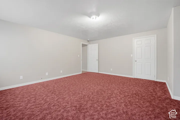 Spacious interior with neutral wall tones, red carpet flooring, and two white paneled doors
