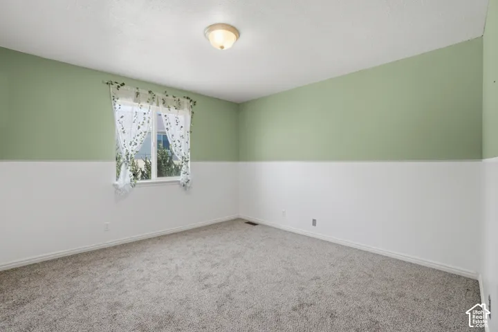 Carpeted room featuring a double-hung window, two-tone painted walls, and a ceiling-mounted light fixture