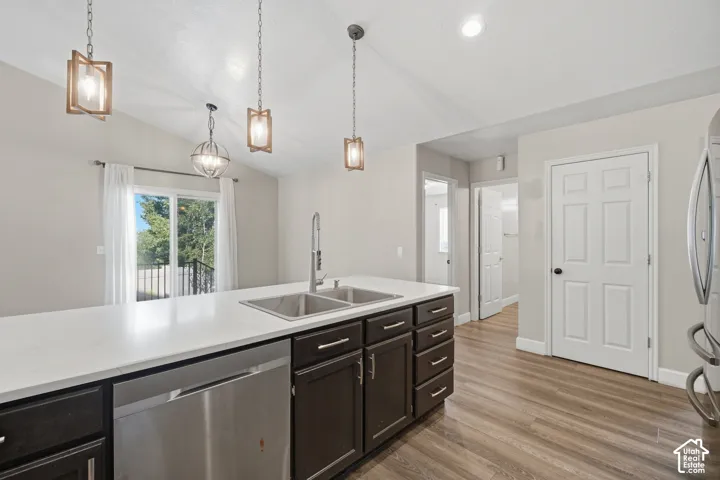 Kitchen island with white countertop, dual stainless steel sinks, dark wood-finish cabinetry, and an integrated stainless steel dishwasher