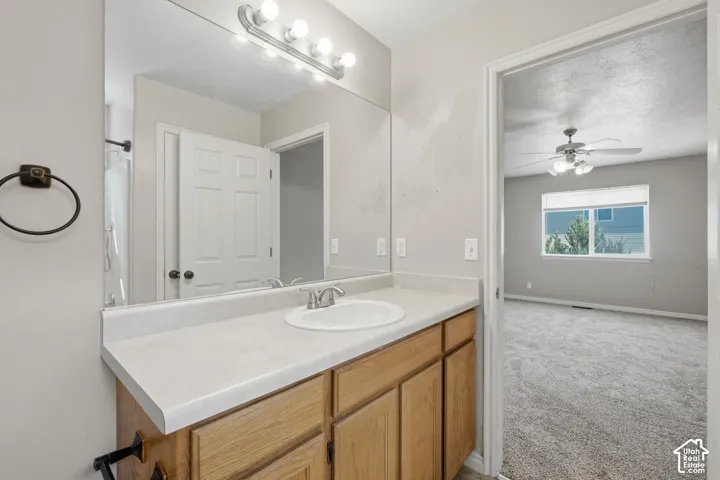 Bathroom vanity with a single basin sink, laminate countertop, and wood-finish cabinetry