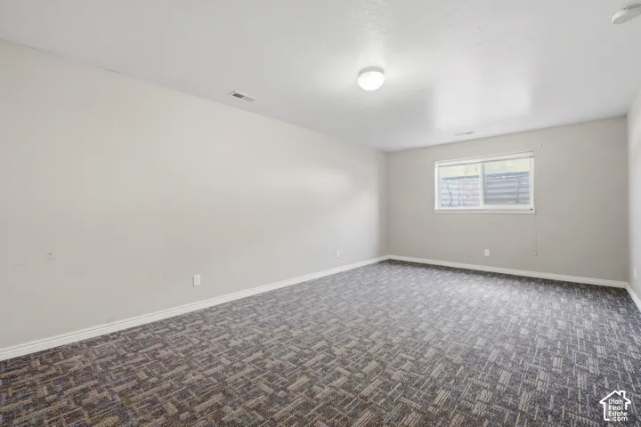 Wall-to-wall patterned carpeting, light-toned walls, and a window with horizontal blinds