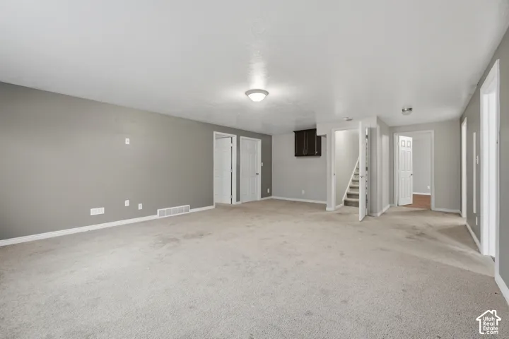 Spacious room with light gray walls, white trim, and carpet flooring