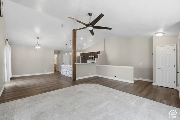 Vaulted ceiling with an exposed wood beam, wood-finish flooring, and a ceiling fan