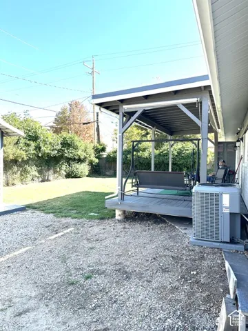 Covered outdoor patio with a gray wood-finish deck, surrounded by a gravel and grassy yard