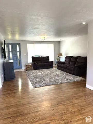 Wood-finish flooring, bay window, ceiling-mounted light fixture, recessed lighting, and a paneled entry door with vertical glass inserts