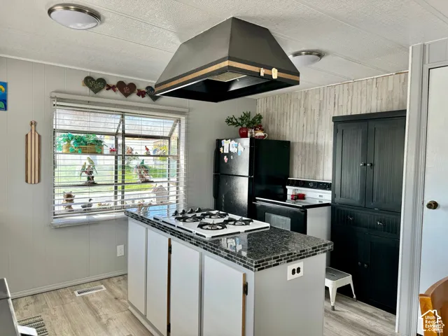 Kitchen featuring a center island with a built-in cooktop, tile countertop, and white cabinetry