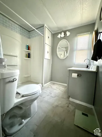 Bathroom featuring a shower with light blue subway tile surround, built-in storage cabinetry, a vanity with an integrated sink, and an oval mirror