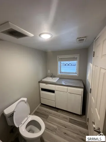 Bathroom featuring a vanity with integrated sink, wood-finish flooring, and a window for natural light