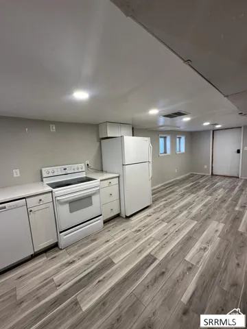 White appliances, wood-finish flooring, white cabinetry, recessed lighting, and a neutral wall color