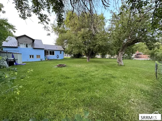 Expansive green lawn with mature trees and a metal fence line