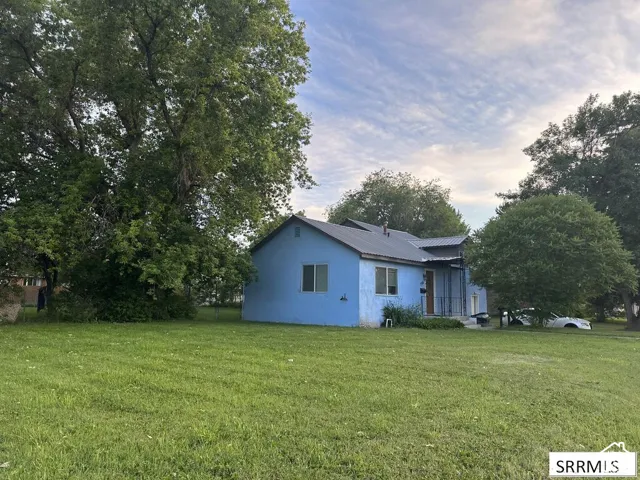 Expansive lot featuring a blue exterior residence with a covered porch and mature trees
