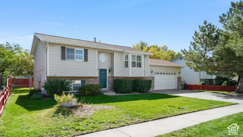 Two-story residence with light-toned siding, attached two-car garage, and a manicured lawn