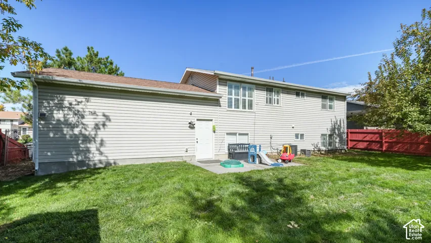 Expansive backyard featuring a manicured lawn, concrete patio, and privacy fencing