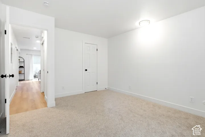 Neutral-toned carpet flooring with white walls and a white paneled door with black hardware