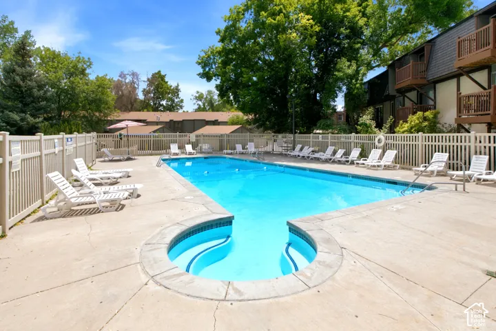 Outdoor swimming pool with concrete decking, integrated spa, and surrounding picket fencing