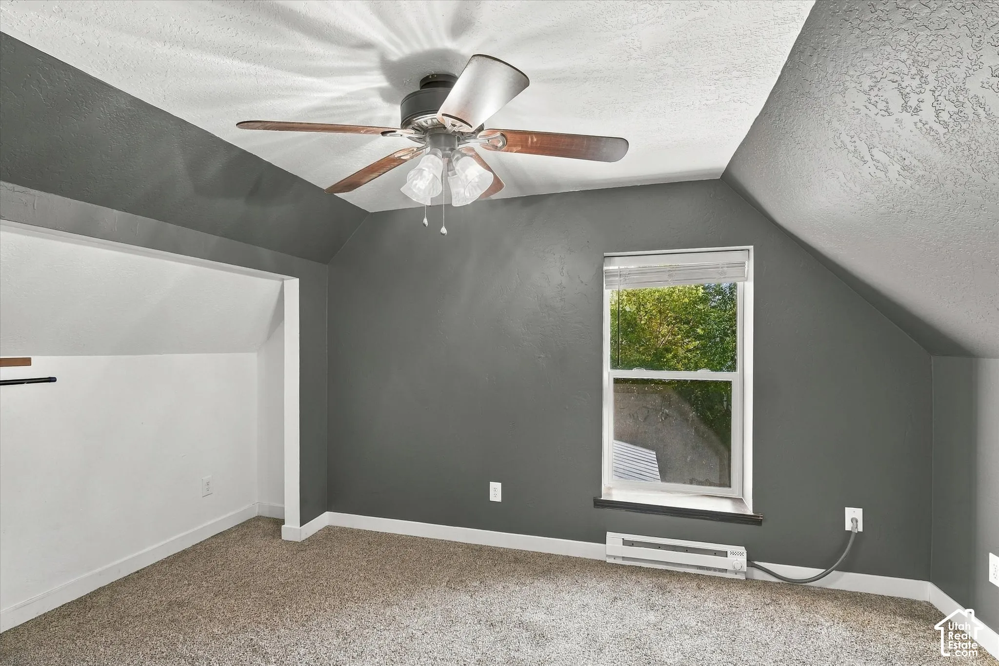 Spacious bedroom with angled ceilings and abundant natural light from a large double-hung window