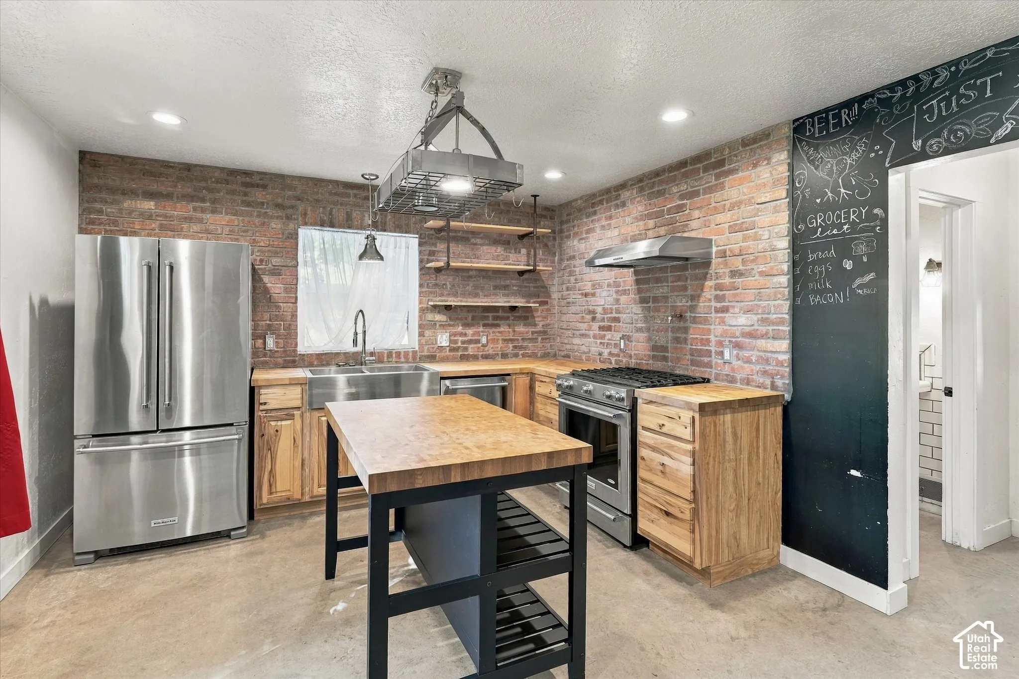 Exposed brick wall, stainless steel appliances, wood-finish countertops, central island, and open shelving