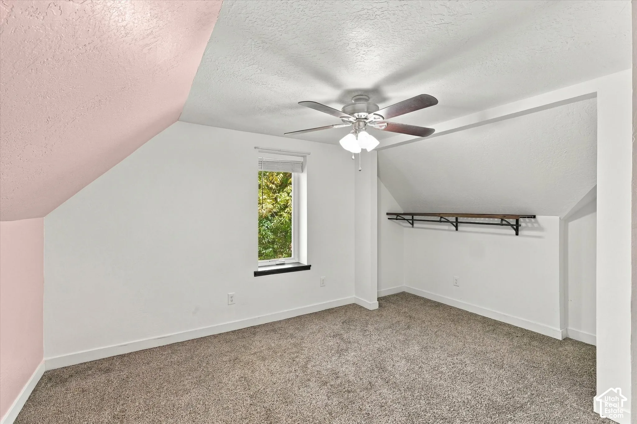 Angled ceiling, recessed window, carpeted flooring, built-in shelving, and ceiling fan with integrated lighting
