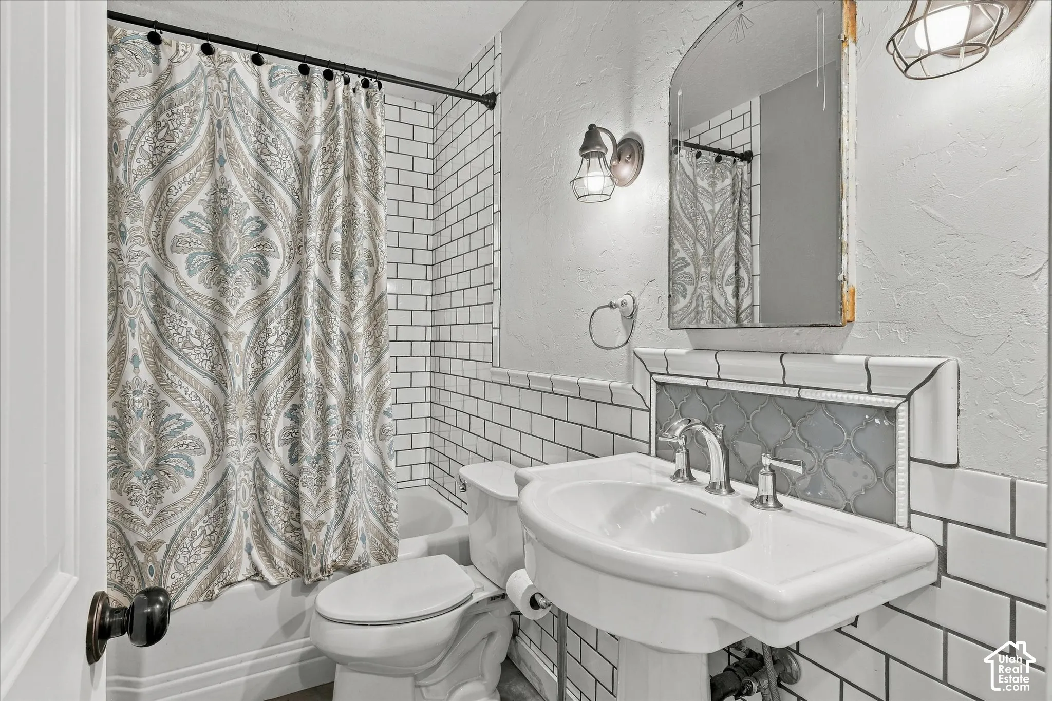 Subway tile wainscoting, pedestal sink, chrome fixtures, built-in tiled shelving, and wall-mounted lighting