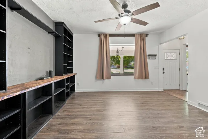 Built-in shelving with wood-finish countertop, wood-finish flooring, ceiling fan, and decorative glass panel entry door