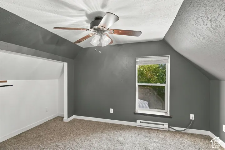 Spacious bedroom with angled ceilings and abundant natural light from a large double-hung window