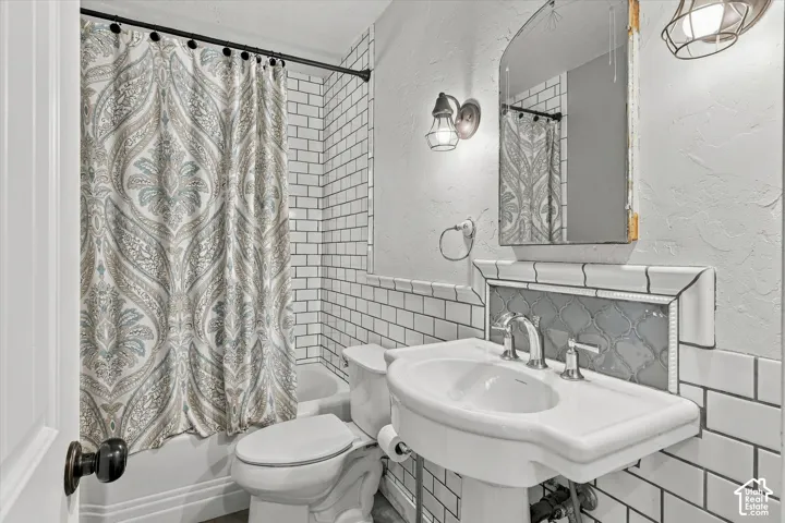 Subway tile wainscoting, pedestal sink, chrome fixtures, built-in tiled shelving, and wall-mounted lighting