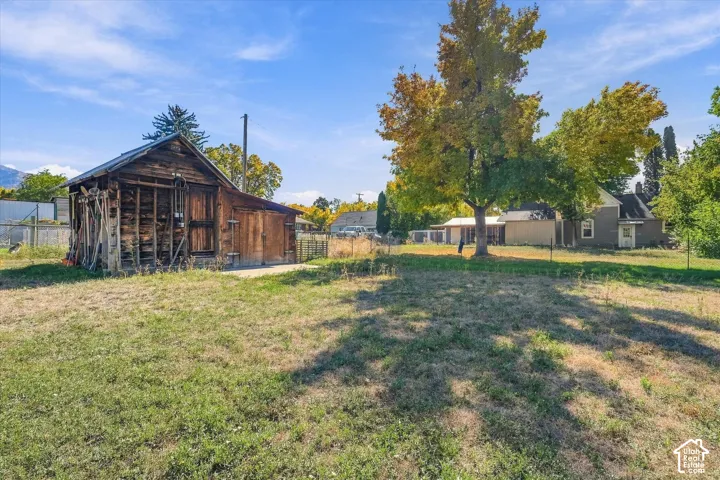 Spacious rural property featuring mature shade trees, expansive open grounds, and multiple outbuildings including a wood-finish barn structure
