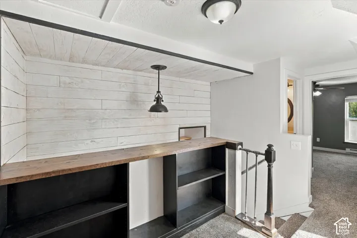 Built-in shelving with a wood-finish countertop, shiplap wall detail, and suspended pendant light