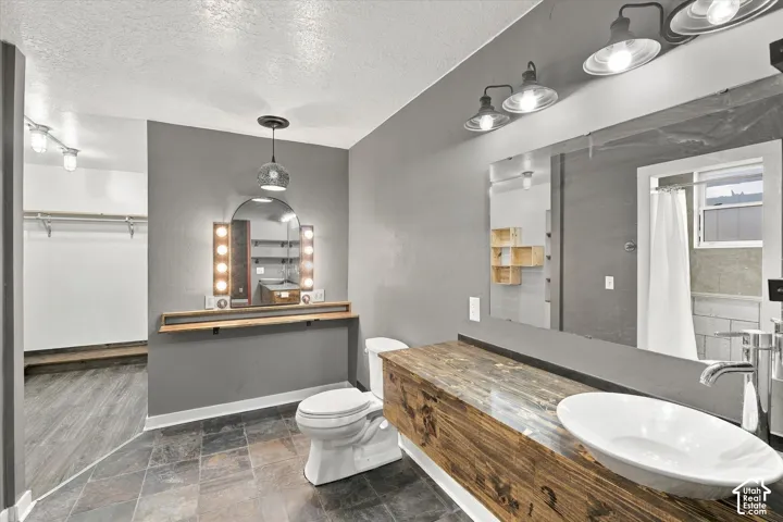 Slate tile flooring, reclaimed wood vanity, vessel sink, full-width mirror, and a makeup vanity with illuminated mirror