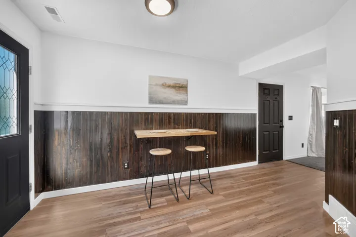 Wood-finish flooring throughout, dark wood paneled wainscoting, white walls, and a ceiling-mounted light fixture