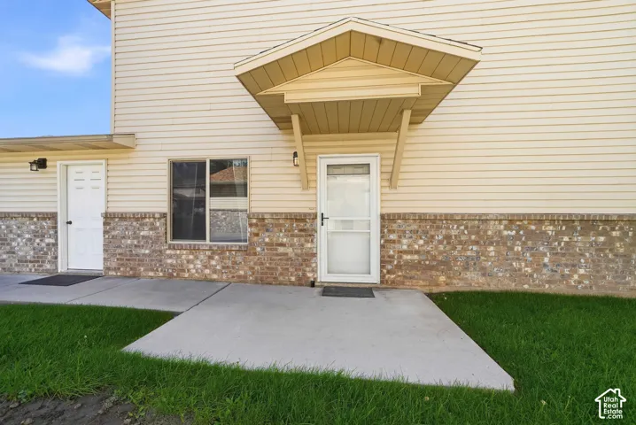 Exterior featuring vinyl siding, a brick facade, and a concrete patio