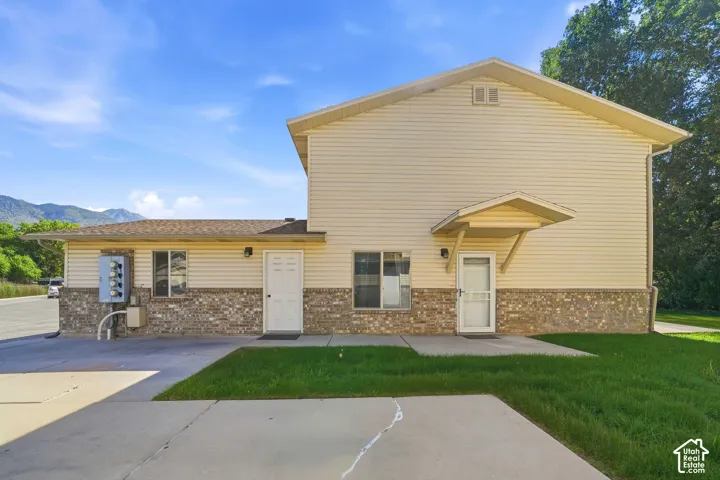 Siding exterior with brick wainscoting, covered entrance, and concrete paving