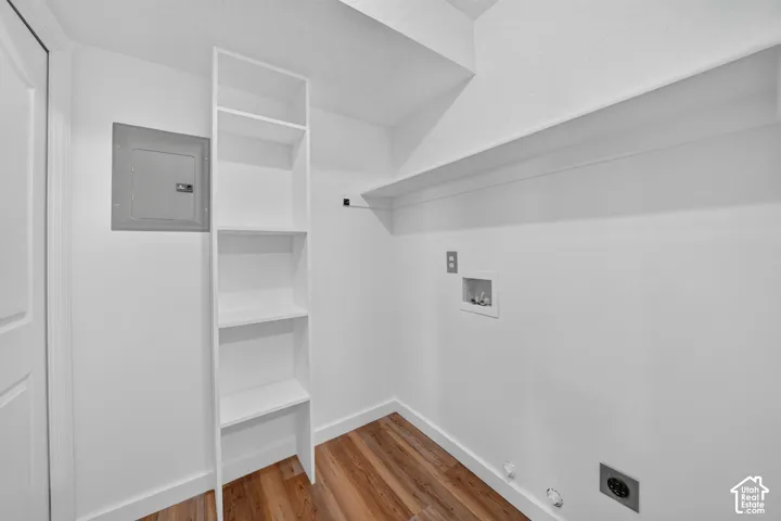 Wood-finish flooring with white trim, built-in shelving, and a wall-mounted electrical panel