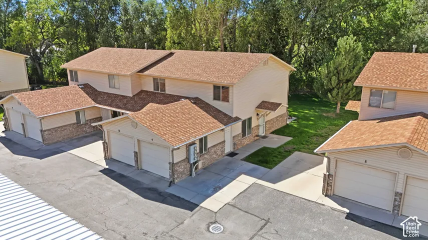 Two-story multi-unit dwelling with pitched shingle roofs