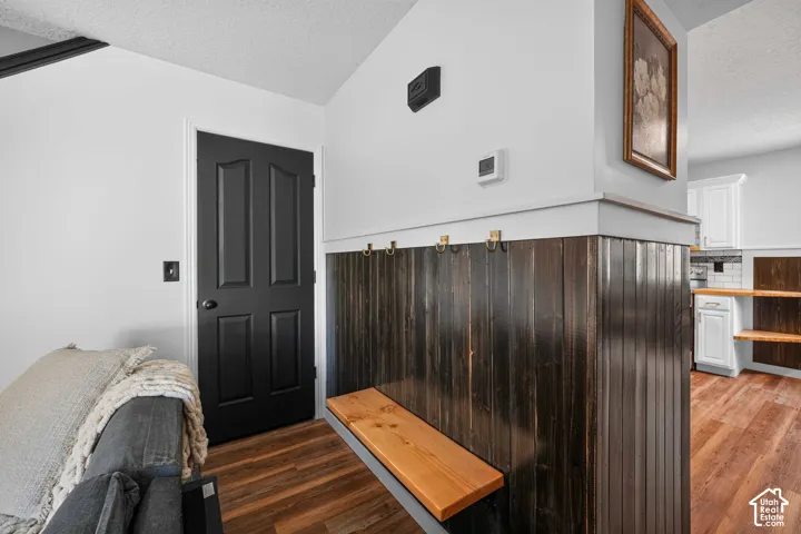 Wood-finish flooring, dark paneled wainscoting, and a built-in wood bench with wall-mounted hooks