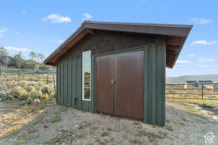 Shed with a sloped roof, vertical siding, and a prominent metal double door