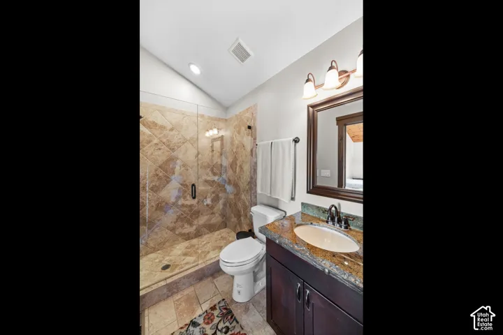Walk-in shower with natural stone tile, glass enclosure, and a built-in bench