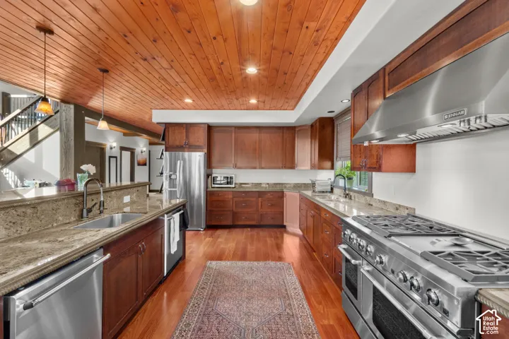 Kitchen featuring wood panel ceiling, wood-finish flooring, wood cabinetry, granite countertops, and stainless steel appliances